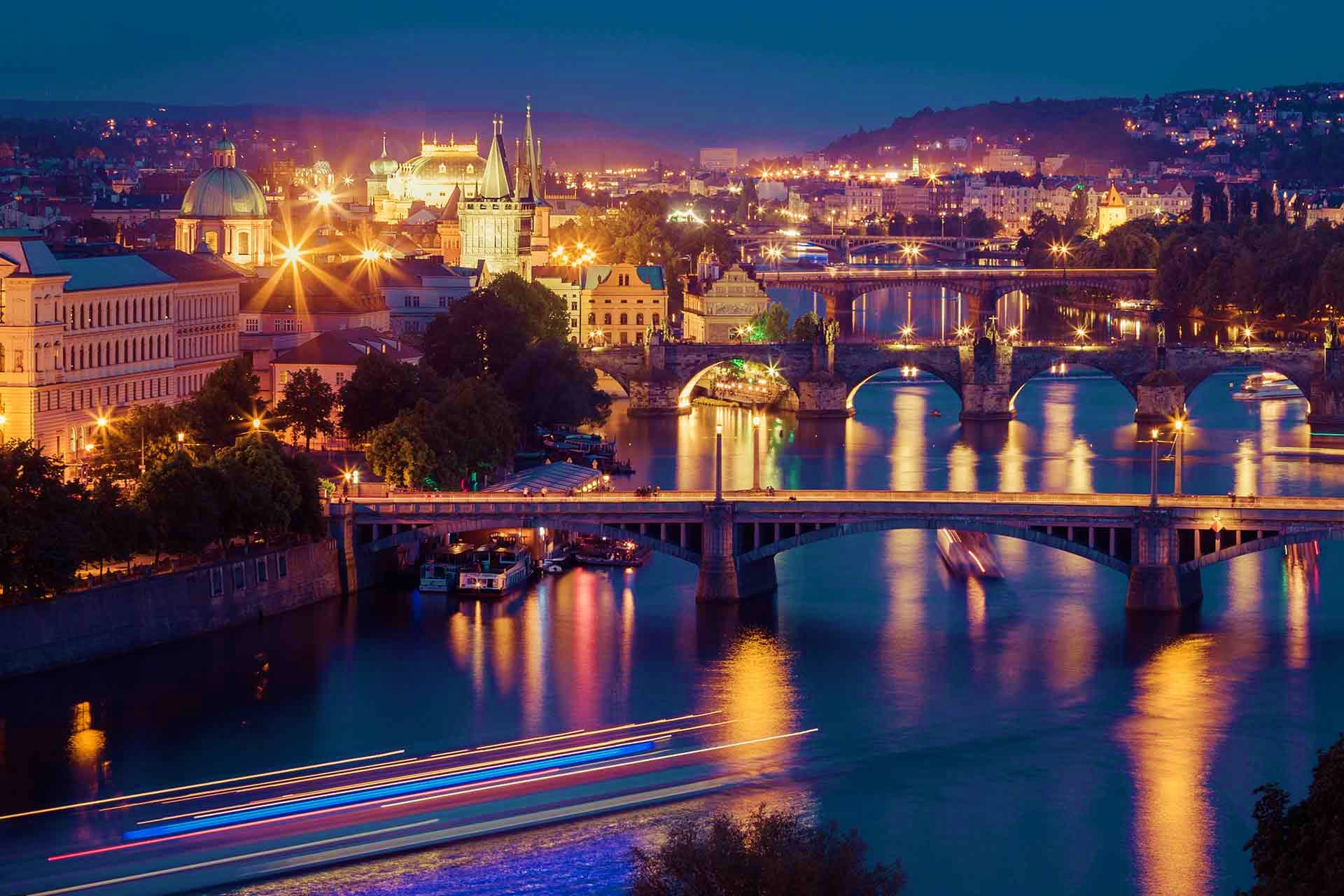 Prague cityscape at night with illuminated Charles Bridge spanning the Vltava River and historic architecture
